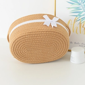 Detail of woven cotton rope storage basket with decorative white bow and side handles