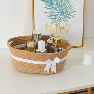 Japanese style hand-woven cotton rope storage basket with white ribbon bow and handles