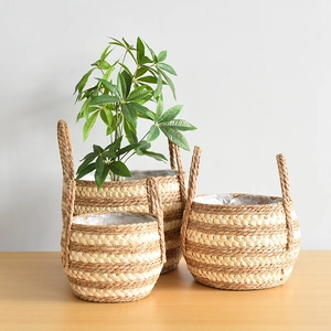 Three-piece Nordic woven seagrass plant baskets with plastic lining on wooden table