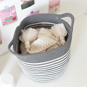 Detail of woven cotton rope storage basket with grey and white striped design and handles