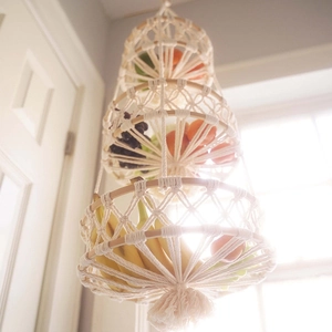 Three-tier macrame fruit basket made of white cotton rope with bohemian tassels