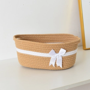 Close-up of hand-woven cotton rope storage basket with decorative white ribbon and bow