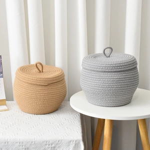 Detail of handmade cotton rope storage baskets with lids in natural and grey tones