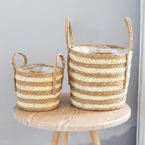 Close-up of two natural woven grass plant baskets with white stripes and waterproof lining