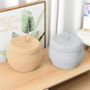 Detail of round cotton rope storage baskets with lids and ring handles in a home setting