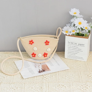 Handmade beige woven straw shoulder bag with floral embroidery on a lace tablecloth