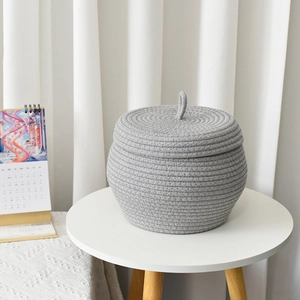 Close-up of handmade gray cotton rope storage basket with lid on a side table