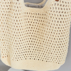 Close-up of beige woven tote bag showing hollow-out knit texture and inner grey lining