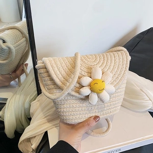 Detail of hand-woven straw crossbody bag with white daisy sunflower and smiley face charm