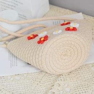 Close-up of beige woven straw bag featuring handmade 3D daisy flower decorations