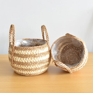 Detail of woven straw plant basket with sturdy handles and waterproof plastic liner