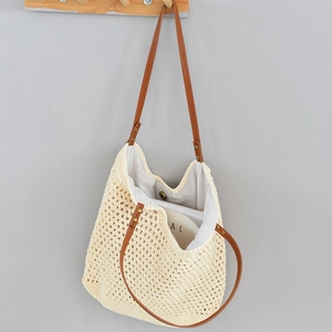 Detail view of woven straw tote bag featuring brown leather straps and secure magnetic closure