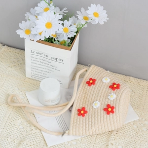 Beige woven crossbody bag with daisy floral details in a French country style setting