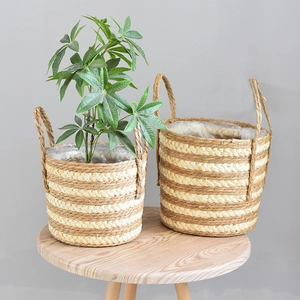 Set of two woven straw plant baskets with handles and waterproof liners in a Nordic style