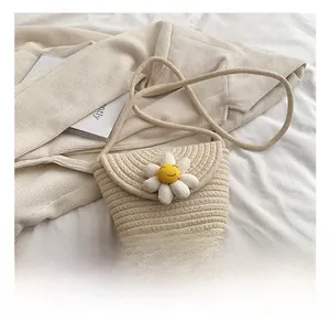 Detail showing handwoven cream crossbody bag with a smiling sunflower decoration
