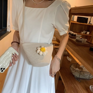 Detailed close-up of woven straw bag with white daisy flower on a rustic wood counter