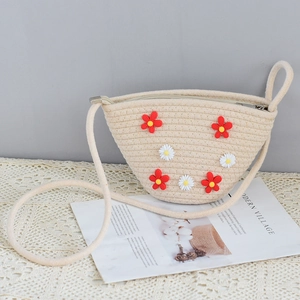 Detail of hand-woven beige straw bag with 3D daisy flower embroidery and zipper closure