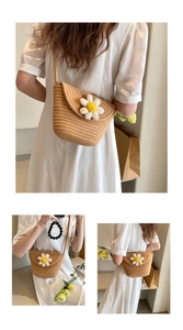 Detail of woven straw crossbody bag featuring a white daisy flower on summer dress