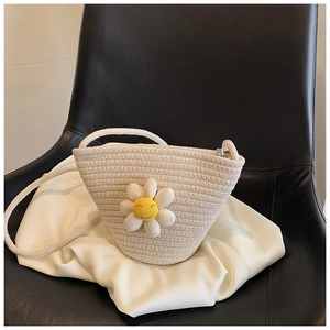 Close-up of woven straw bag with white daisy flower detail and silk fabric background