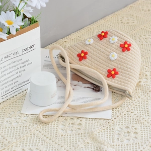 Chic beige straw woven crossbody bag featuring red and white floral daisy appliques