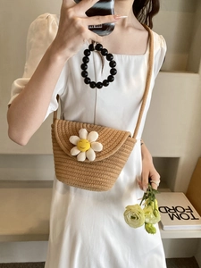 Detail of summer woven crossbody bag featuring a white daisy with a smiling face ornament