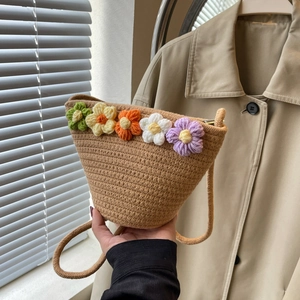 Detail of handmade woven straw bucket bag with colorful 3D knitted flower decorations