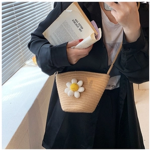 Detail of summer straw crossbody bucket bag with white daisy flower ornament for women