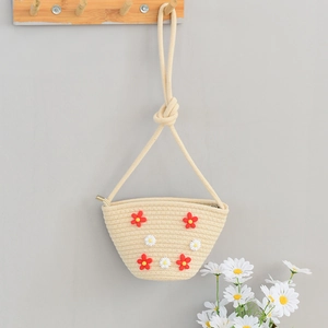 Detail of straw woven bag with floral daisy decorations and a sturdy rope handle