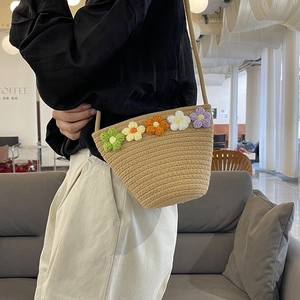 Detail of handmade woven shoulder bag featuring colorful crochet flowers on light khaki straw