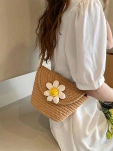 Detailed weave of a straw bag featuring a white daisy flower with a cheerful smiley face