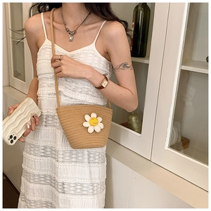 Detailed close-up of handmade straw bucket bag with white daisy applique for summer beach