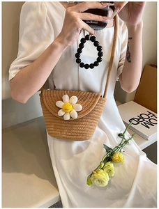 Detail of summer woven straw crossbody bag with cute sunflower decoration on white dress