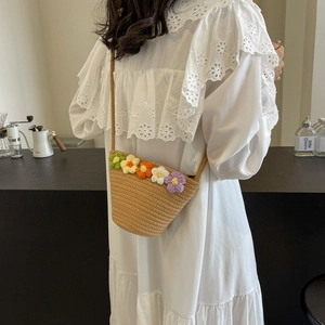 Detail of hand-woven straw crossbody bag with colorful crochet flowers on white dress
