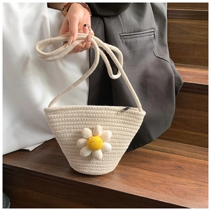 Detailed macro view of woven rope crossbody bag featuring embroidered daisy flower detail