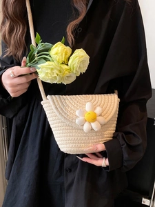 Close-up of a woven straw phone bag featuring a white daisy flower detail for summer
