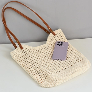 Detail of cream woven beach tote showing mesh texture and brown faux leather handles