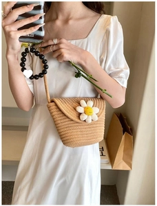 Detailed close-up of a woven mini bucket bag with a white daisy and yellow smiley center