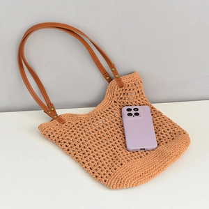 Detail of woven beach tote showing hollow crochet texture and leather strap with studs