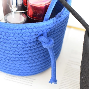 Detail of blue cotton rope woven storage basket with makeup items and side handle