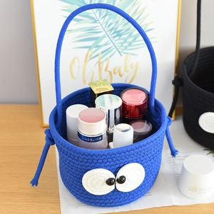 Detail of blue cotton woven basket with cute big eyes storing skincare bottles on a desk