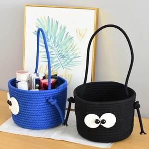 Close-up of blue and black woven cotton storage baskets with big cartoon eyes on a desk