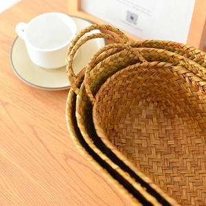 Macro detail of handwoven seagrass storage baskets with handles on a wooden tabletop