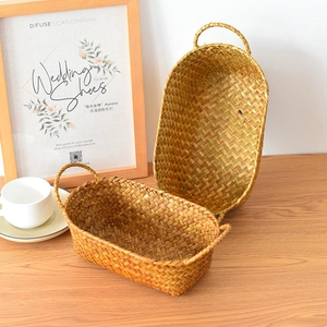 Detailed close-up of natural seagrass woven baskets with circular handles on wood table