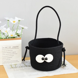 Close-up of black cotton rope storage basket with big eyes design on wooden table