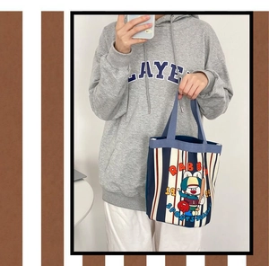 Detailed close-up of blue striped canvas bucket bag with cute cartoon rabbit illustration