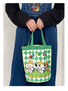 Close-up of canvas bucket bag with green checkerboard pattern and cute cartoon animal prints