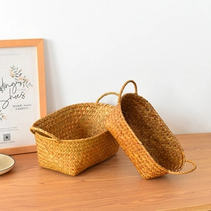 Detail of two handmade woven straw baskets with handles on a rustic wooden table