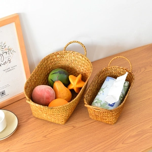 Detail of two handmade woven storage baskets with handles on a wooden table surface