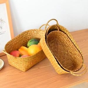 Close-up of natural seagrass woven baskets with dual handles on a rustic wooden table