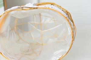 Close-up of golden iron weave basket featuring elegant white lace trim and plastic lining